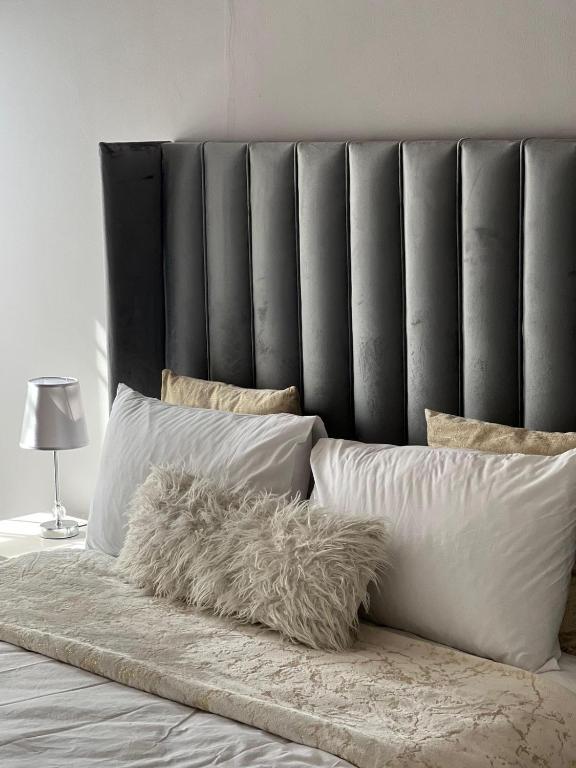 a bed with a black headboard and white pillows at Amari Cottage in Boksburg
