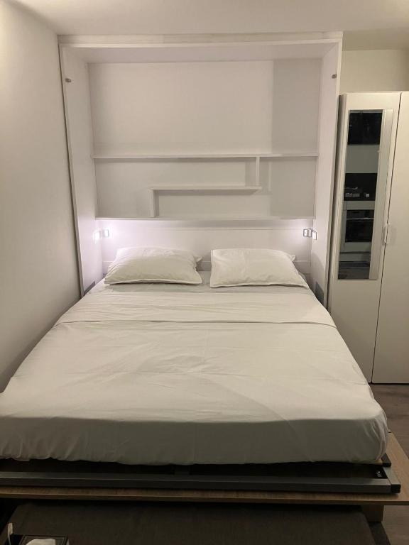 un lit avec des draps blancs et des oreillers dans une chambre dans l'établissement Studio Colonel MOLL, à Vaires-sur-Marne