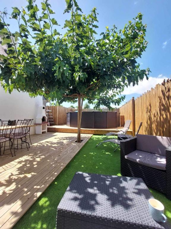 une terrasse avec un arbre, une table et des chaises dans l'établissement Maison Bretonne avec piscine, à Marzan