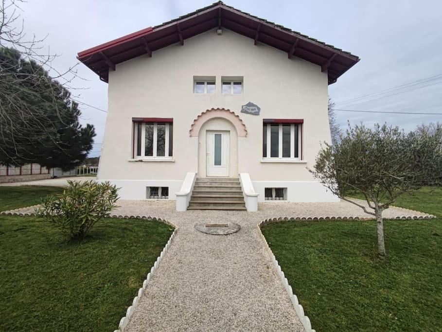 une maison blanche avec deux chaises blanches devant elle dans l'établissement Maison, à Neuvic