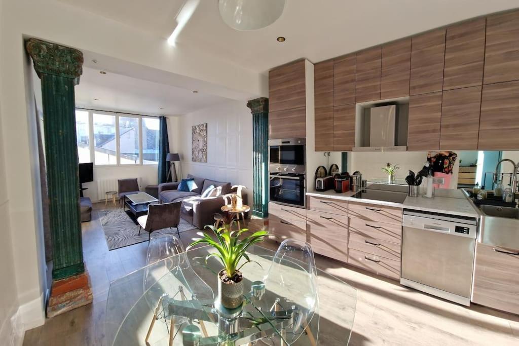 Il comprend une cuisine et un salon avec une table en verre. dans l'établissement Appartement atypique clair et spacieux avec jardin, à Trouville-sur-Mer