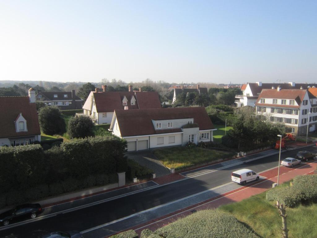 a city street with houses and a white car on the road at Zoutezoute in Knokke-Heist