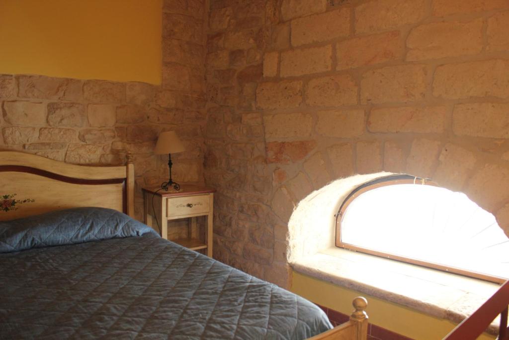 una camera da letto con un muro di mattoni, un letto e una finestra di Case Vacanza ARCO SANT'ANTONIO a Bisceglie