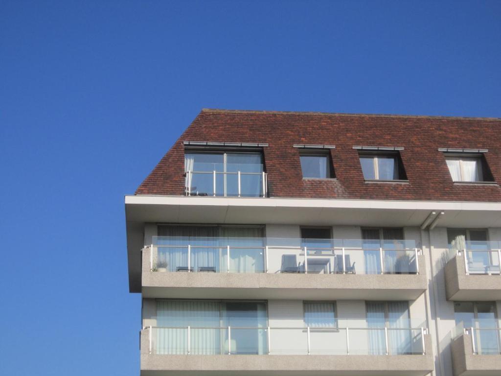 a tall apartment building with a red roof at Zoutezoute in Knokke-Heist