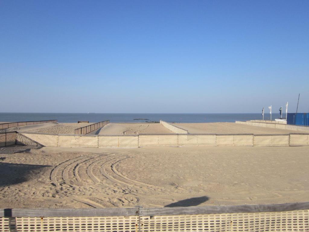 a sandy beach with a fence and the ocean at Zoutezoute in Knokke-Heist