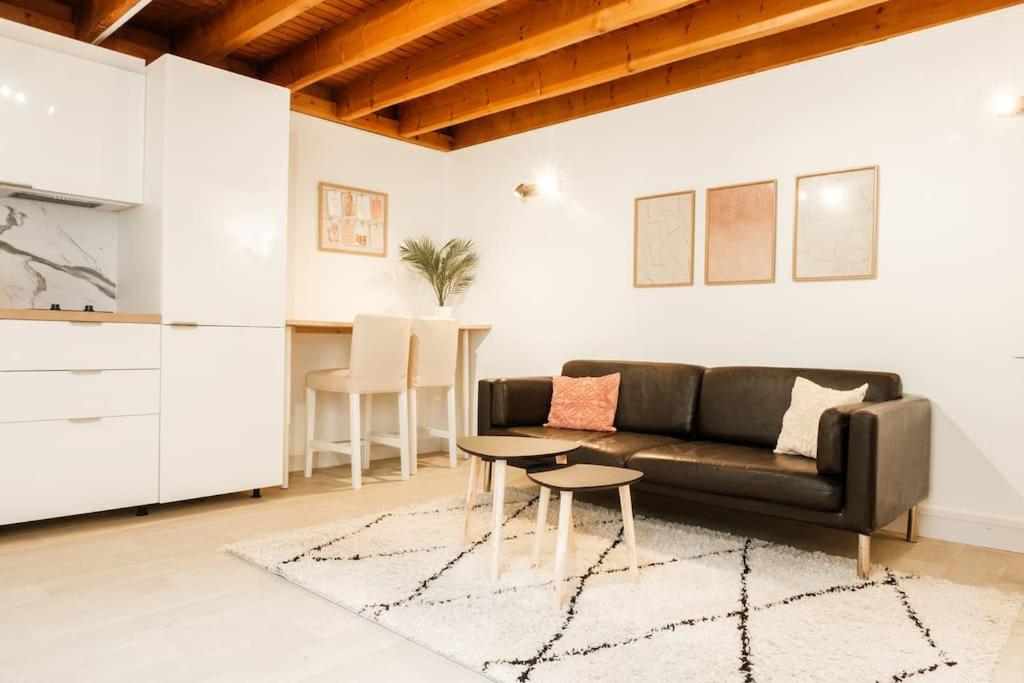 un salon avec un canapé noir et une table dans l'établissement Logement entier Maison, à Versailles