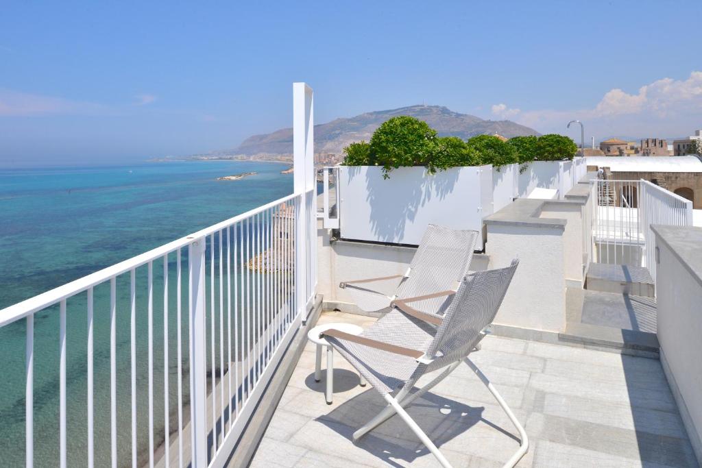 un paio di sedie su un balcone con vista sull'oceano di Gaura Apartments a Trapani