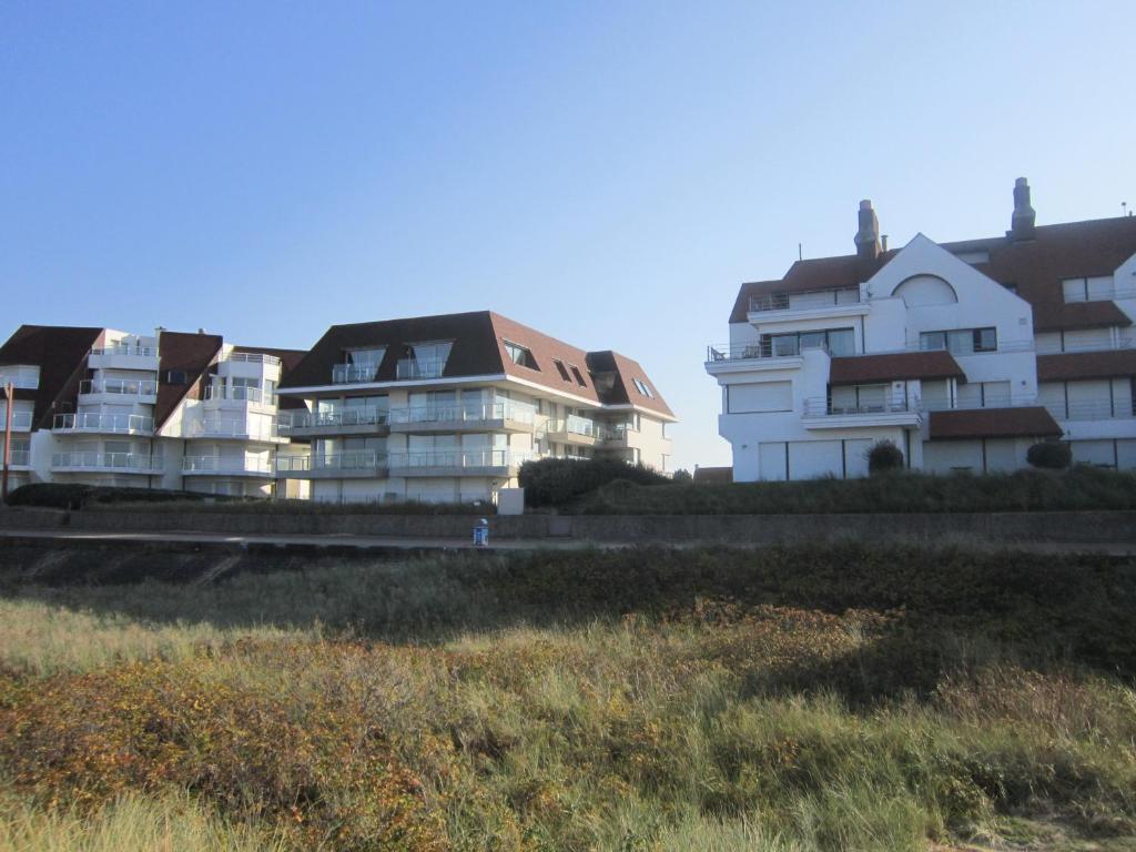 a group of white buildings sitting next to a field at Zoutezoute in Knokke-Heist