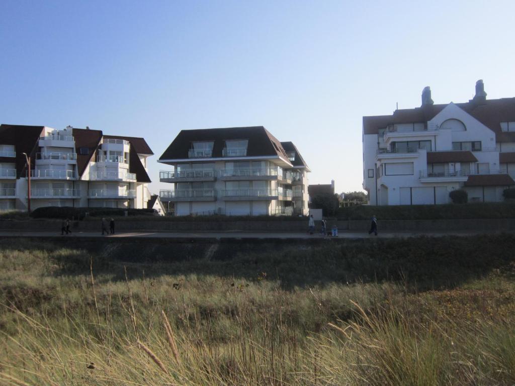 a group of white buildings sitting next to a field at Zoutezoute in Knokke-Heist