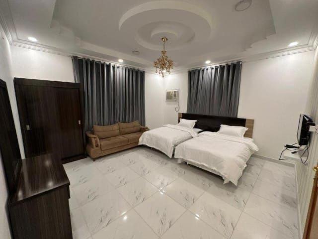 a large bedroom with a bed and a couch at منازل الباحة للشقق الفندقية in Al ‘Āmirah