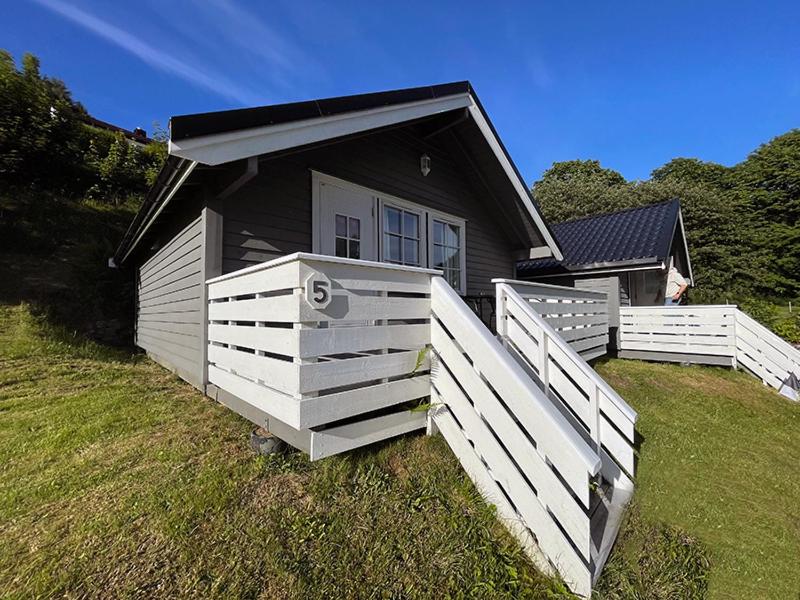 a small house with a white fence in front of it at Selje Camping - Hytte Nr 5 in Selje