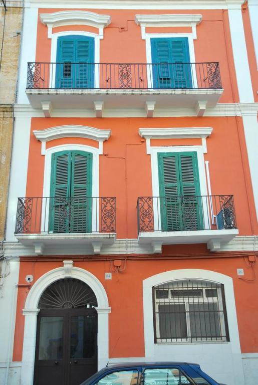 um edifício laranja com janelas azuis e um carro estacionado em frente em Appartamento Aurora em Bari