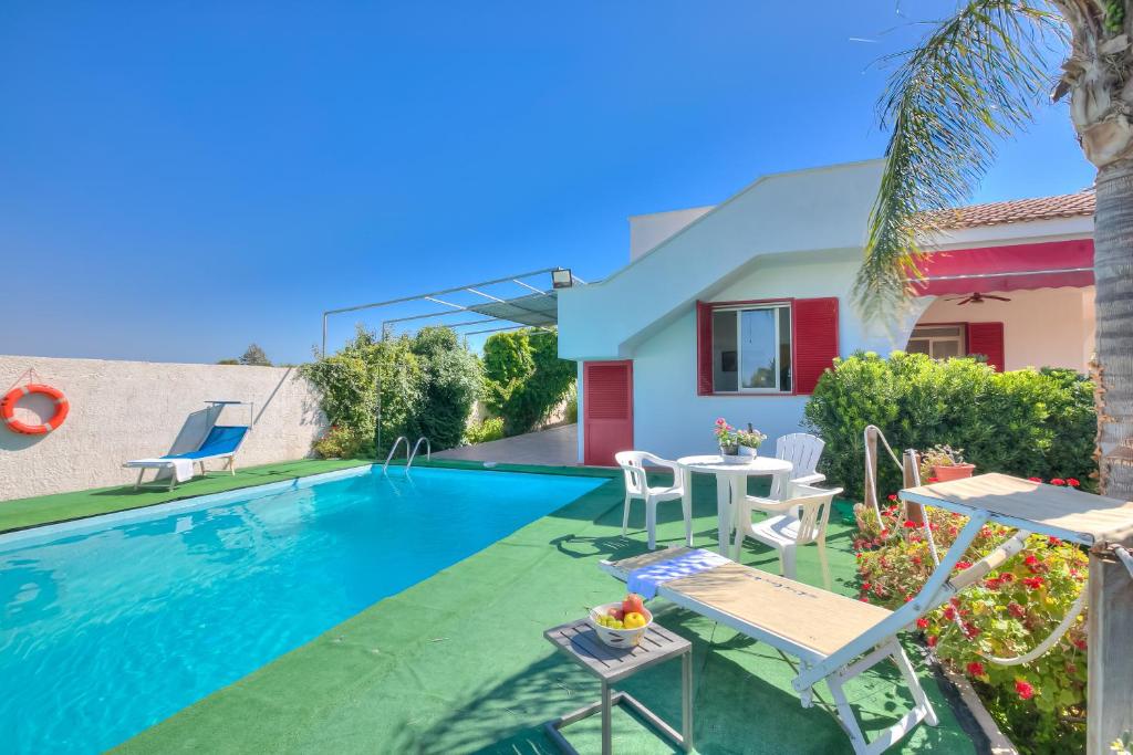 - une piscine avec une table et des chaises à côté d'une maison dans l'établissement Villa Strea With Pool - Happy Rentals, à Porto Cesareo