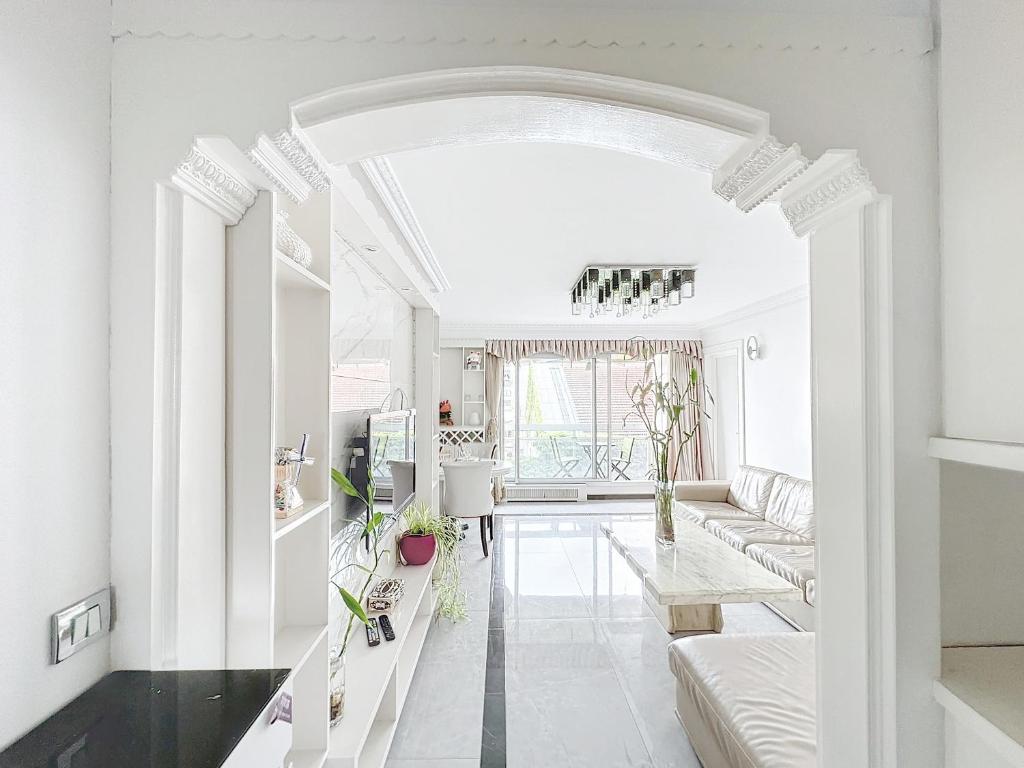 un salon blanc avec un canapé et une table dans l'établissement 115 - Paris, Appartement luxueux spacieux avec vue panoramique, à Paris