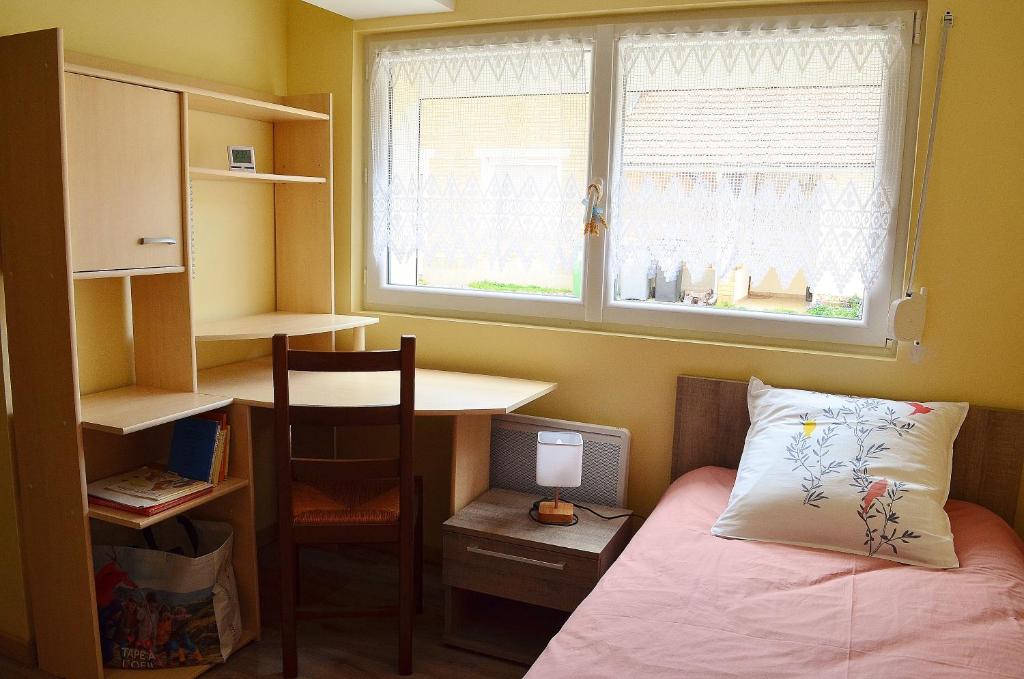 a bedroom with a bed and a desk and a window at La maison d'Arthur et Armelène in Rely