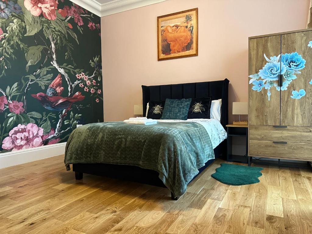a bedroom with a bed and a large floral wallpaper at Rosie Cosy House Cricklewood in London