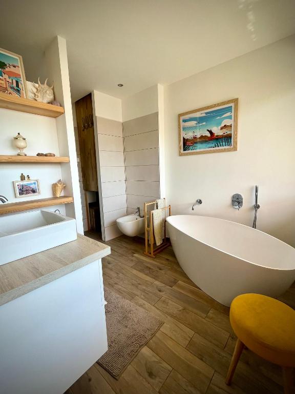 La salle de bains est pourvue d'une grande baignoire blanche et d'un lavabo. dans l'établissement La londe les Maures Location saisonnière Grand Toit-Terrasse, à La Londe-les-Maures