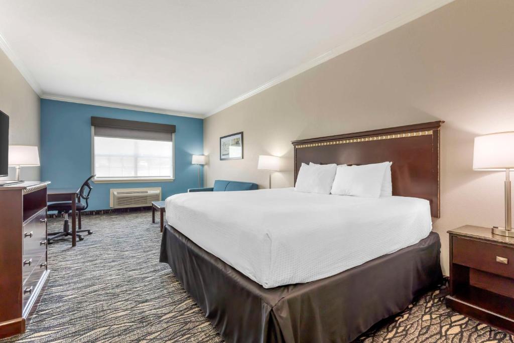 a hotel room with a large bed and a desk at Best Western Plus Lake Worth Inn & Suites in Lake Worth