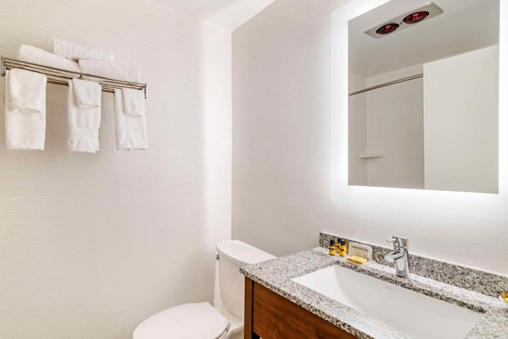a bathroom with a toilet and a sink and a mirror at Best Western Springfield Hotel in Springfield