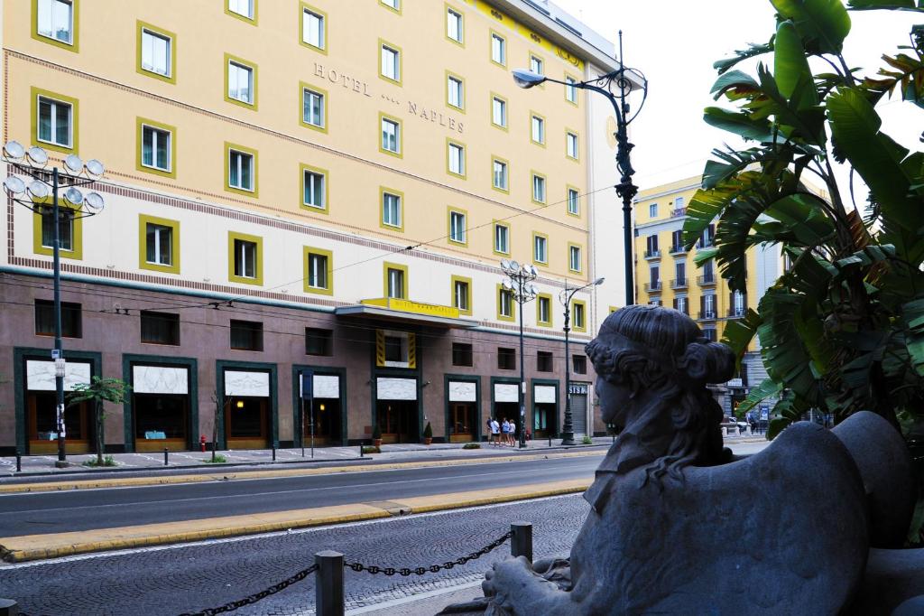una estatua de una mujer sentada en el costado de una calle en Hotel Naples en Nápoles