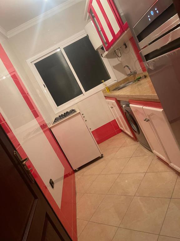 Elle comprend une petite cuisine avec des placards blancs et une fenêtre. dans l'établissement Appartement à Tanger, à Tanger