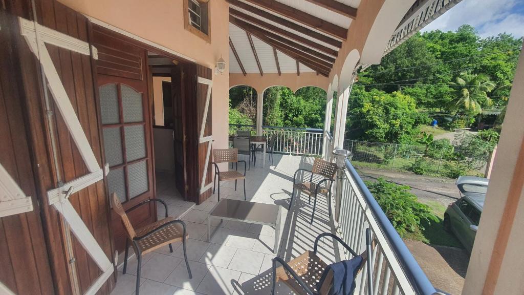 a balcony of a house with chairs and tables at Au cœur de douenel bouillante cheques vacances acceptées in Bouillante