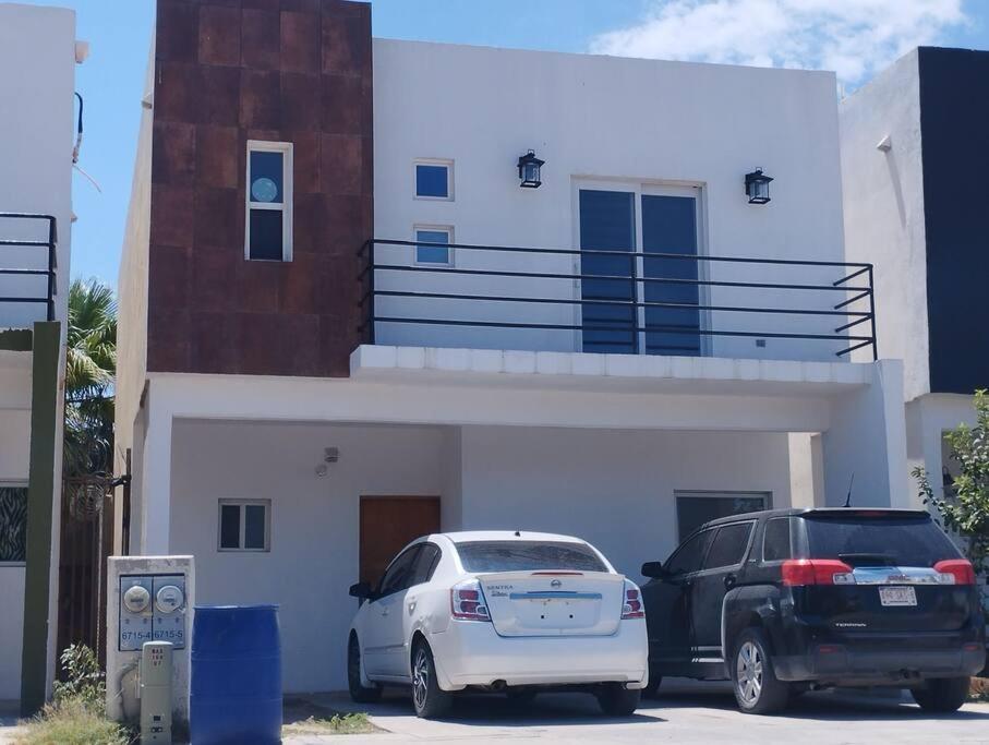 Dos coches estacionados en un estacionamiento frente a una casa. en Hermosa casa a 5 minutos del consulado Americano, cuenta con 3 recamaras, sistema de refrigeración y calefacción, en Ciudad Juárez