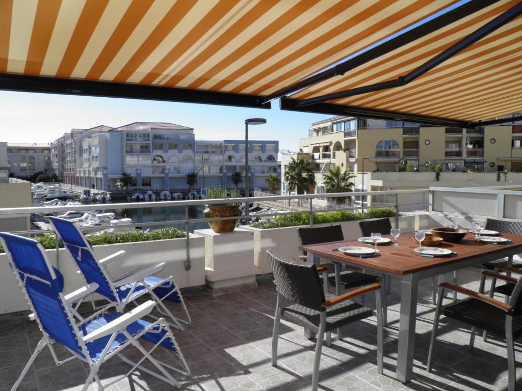 un patio avec une table et des chaises sur un balcon dans l'établissement Appartement moderne, 2 pièces cabine, terrasse et véranda, proche plage, parking privé - FR-1-338-133, à Sète