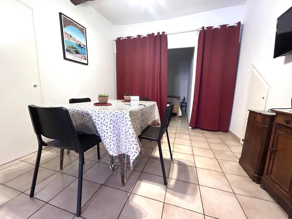 une table à manger avec des chaises et un rideau rouge dans l'établissement Appartement F3 charmant au cœur de Collioure, à 2 pas de la plage et des commerces - FR-1-309-284, à Collioure