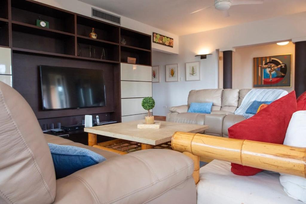 a living room with couches and a tv and a table at Villa Granada at Dorado Beach Resort pool nearby in Dorado