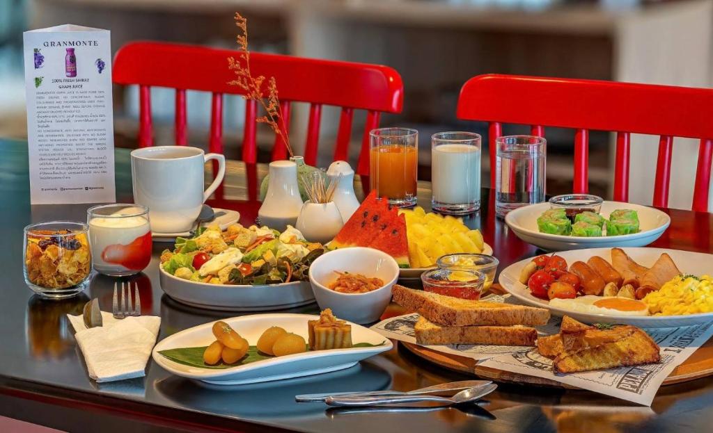 A fully set breakfast table with hot food, fruit, salad, drinks and pastries.