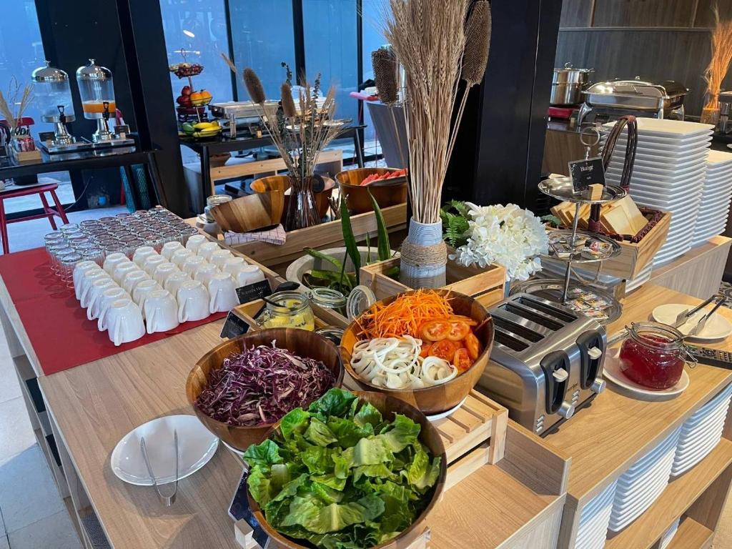 A bright buffet station with salad ingredients, drinks, toast and stacked plates.