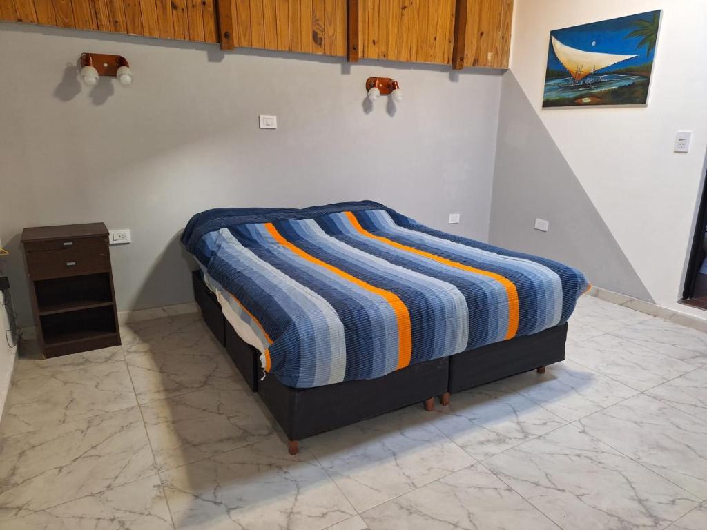 a bed with a colorful striped blanket on the wall at Espacioso dúplex, ubicación premium in San Luis