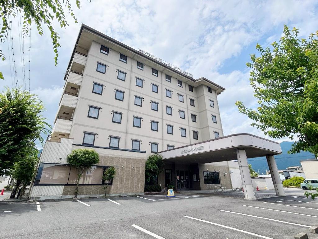 un gran edificio blanco con aparcamiento en Hotel Route-Inn Iida, en Iida