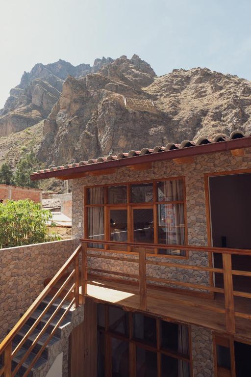 a house with a balcony with a mountain in the background at Casa Alba Ollantaytambo in Ollantaytambo