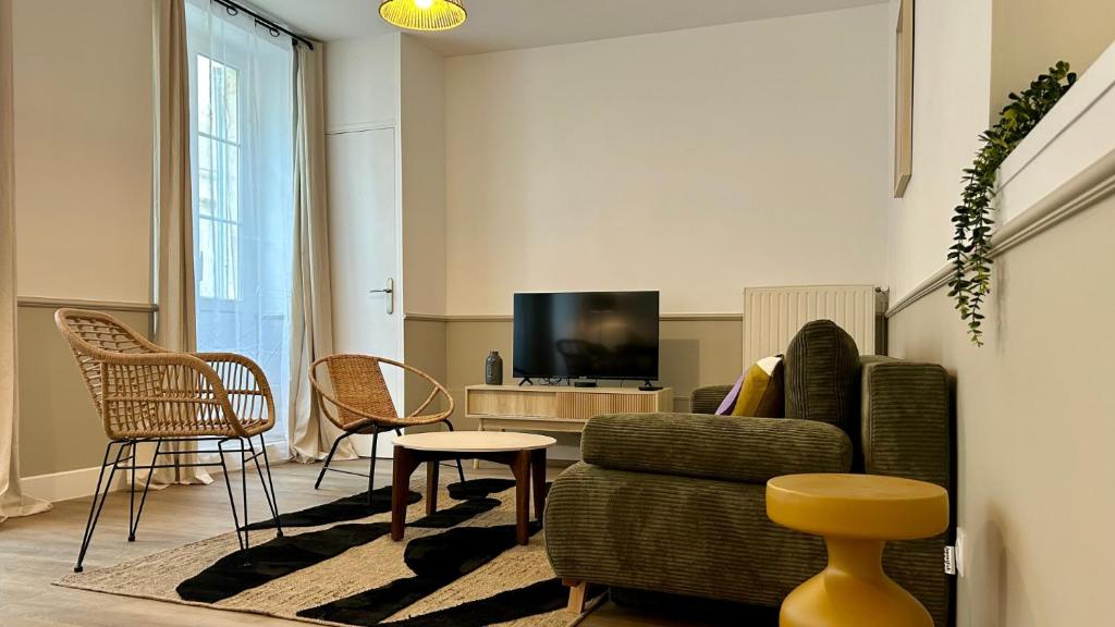 a living room with a couch and chairs and a tv at Charlie Green in Nevers