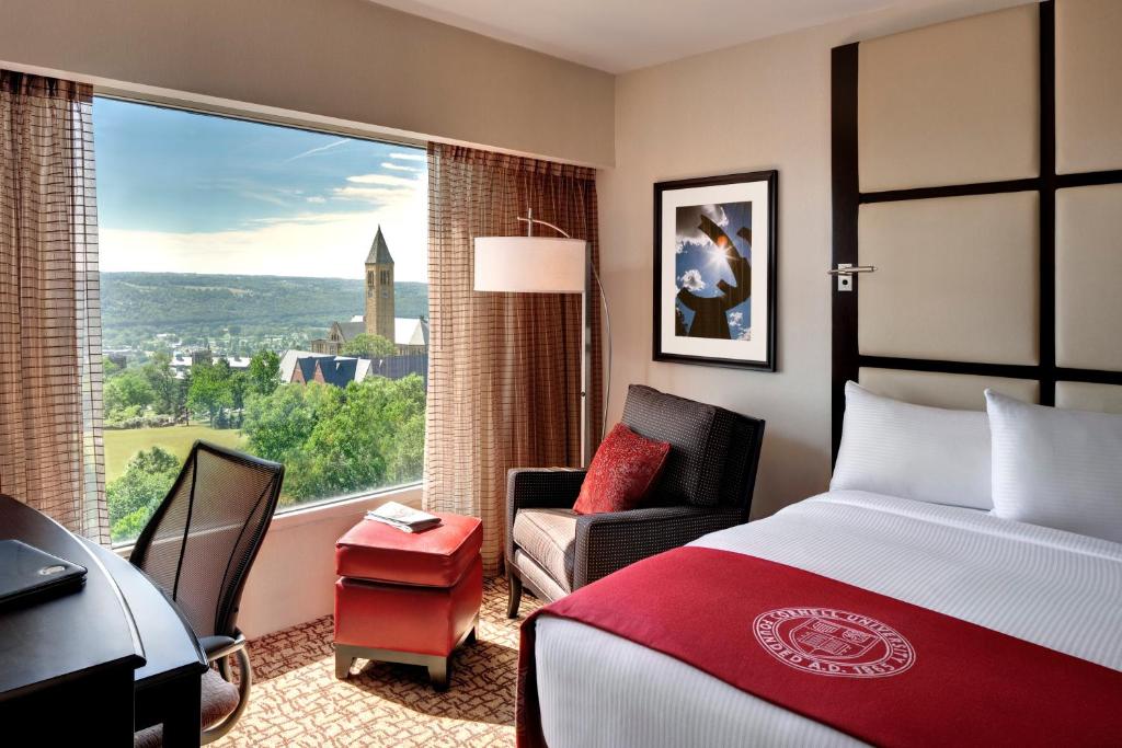 a hotel room with a bed and a desk and a window at The Statler Hotel at Cornell University in Ithaca