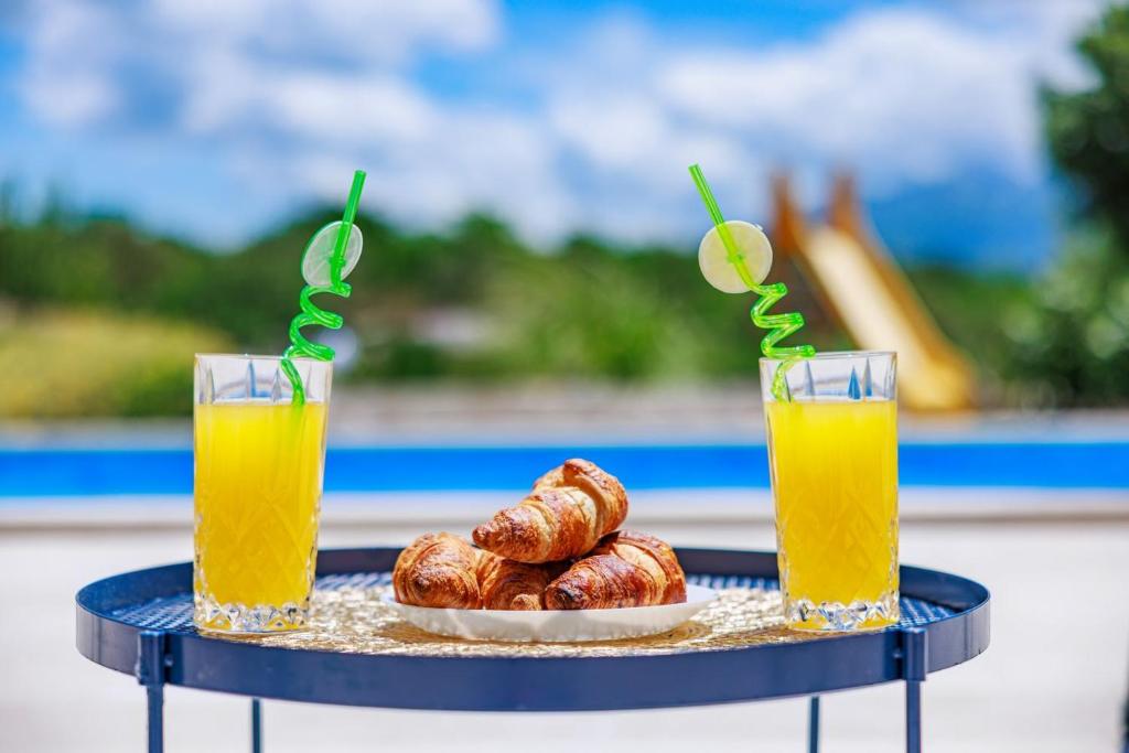 two glasses of orange juice and a plate of pastries at Perfect holiday in Vila Hany home in Šestanovac