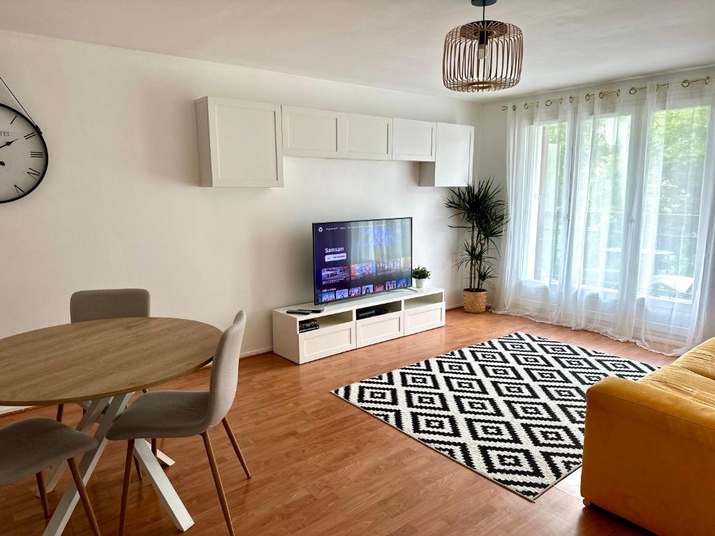 un salon avec une table et une télévision dans l'établissement Charmant appart avec vue sur lac, à Savigny-le-Temple