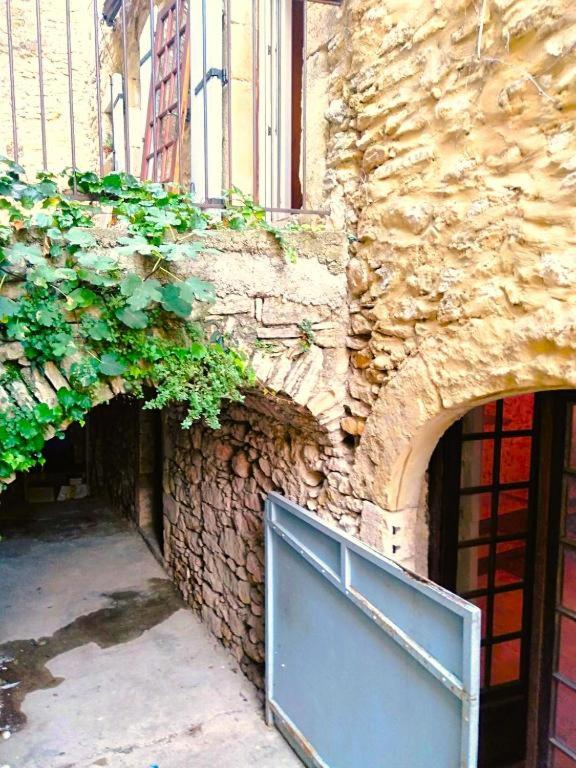 un bâtiment en pierre avec une porte bleue sur son côté dans l'établissement Spacieuse maison de village de caractère pour 10 personnes, à Saint-André-de-Roquepertuis