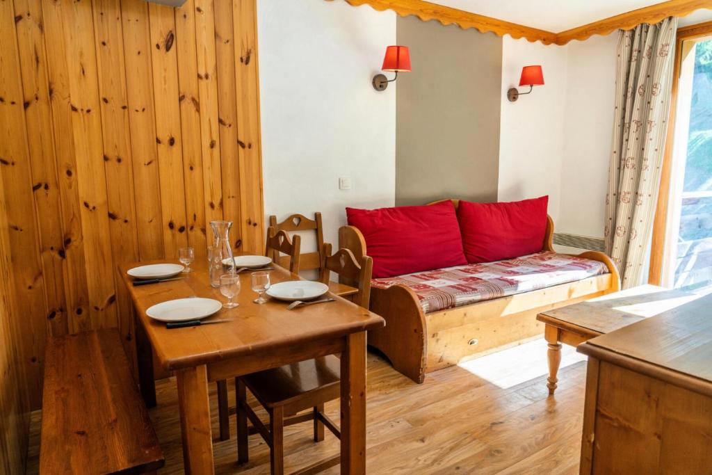 Cette chambre comprend une table et un lit avec des oreillers rouges. dans l'établissement Résidence Les Hauts De Preclaux - Appartement avec vue sur les pistes MAE-7591, aux Orres