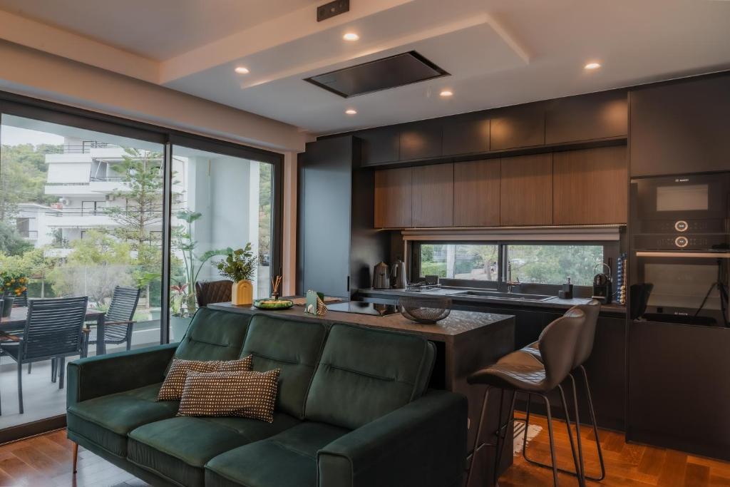 a living room with a green couch and a kitchen at Emerald Stone Apartment Varkiza in Vari