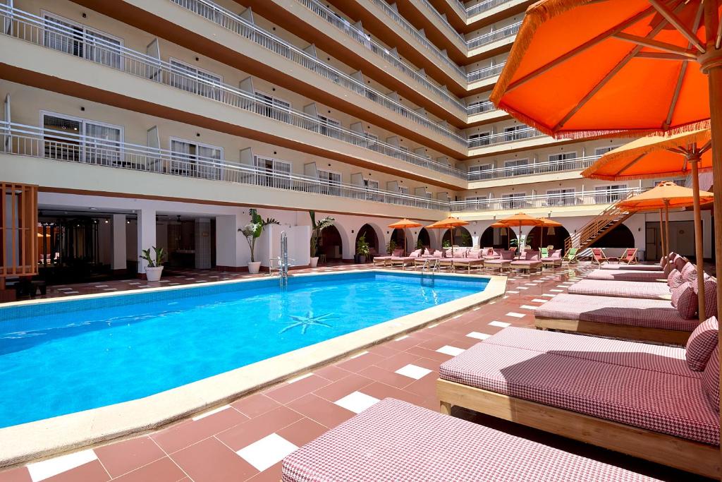 a swimming pool in a building with chairs and umbrellas at tent Bahia de Palma in El Arenal