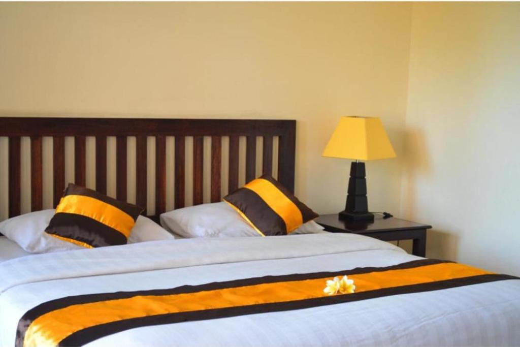 a bed with orange and black pillows and a lamp at Nirmala Hotel & Convention Centre in Denpasar