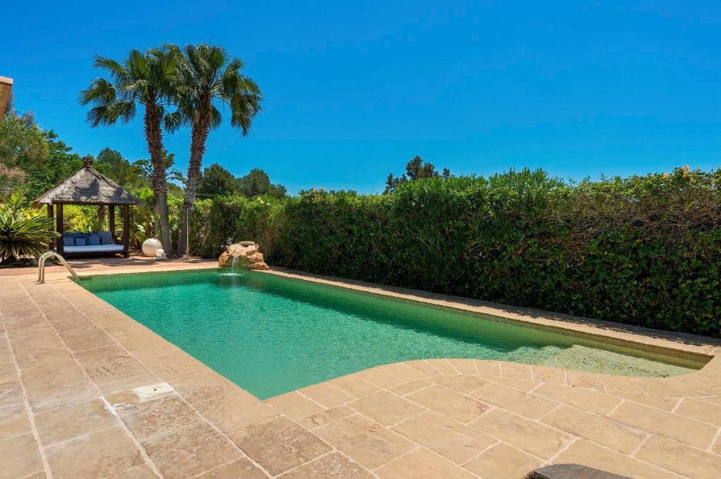 a swimming pool with a gazebo and palm trees at Can Botanic in Sant Josep de sa Talaia