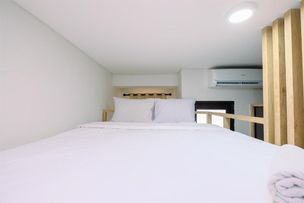 a bedroom with a bed with white sheets at Minimalist and Good Deal Studio Transpark Cibubur Apartment By Travelio in Depok