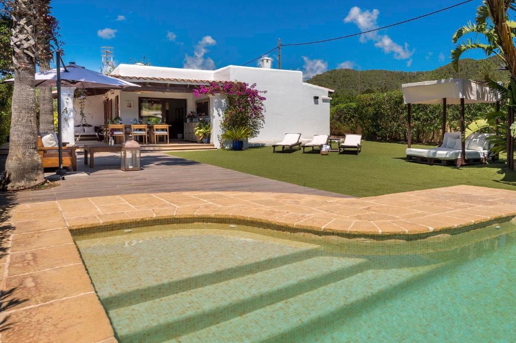a backyard with a swimming pool and a house at Can Botanic in Sant Josep de sa Talaia
