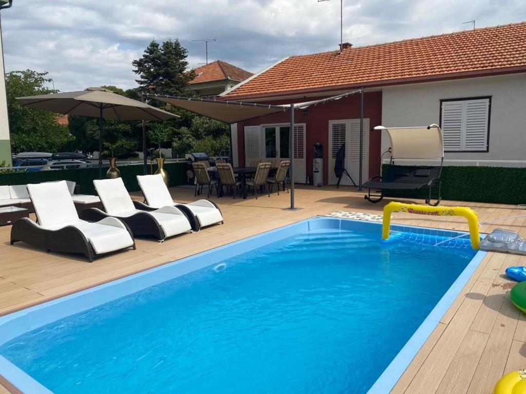 a swimming pool with chairs and an umbrella at Kuća za odmor AMIGO in Sveti Filip i Jakov