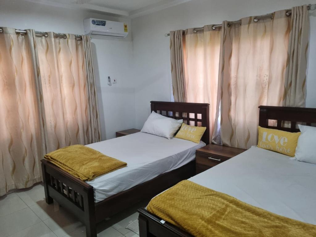 two twin beds in a room with curtains at D11 New Oak in Accra