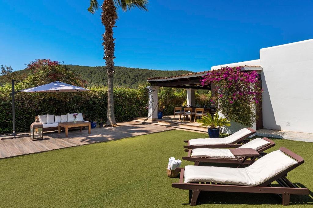 a lawn with lounge chairs and an umbrella at Can Botanic in Sant Josep de sa Talaia